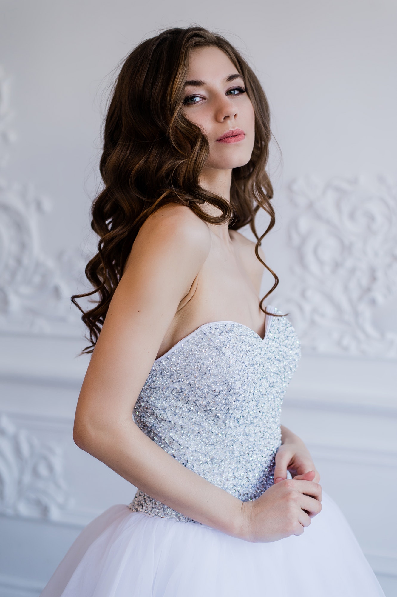 Close portrait of beautiful smiling bride woman with long curly hair posing in wedding dress at