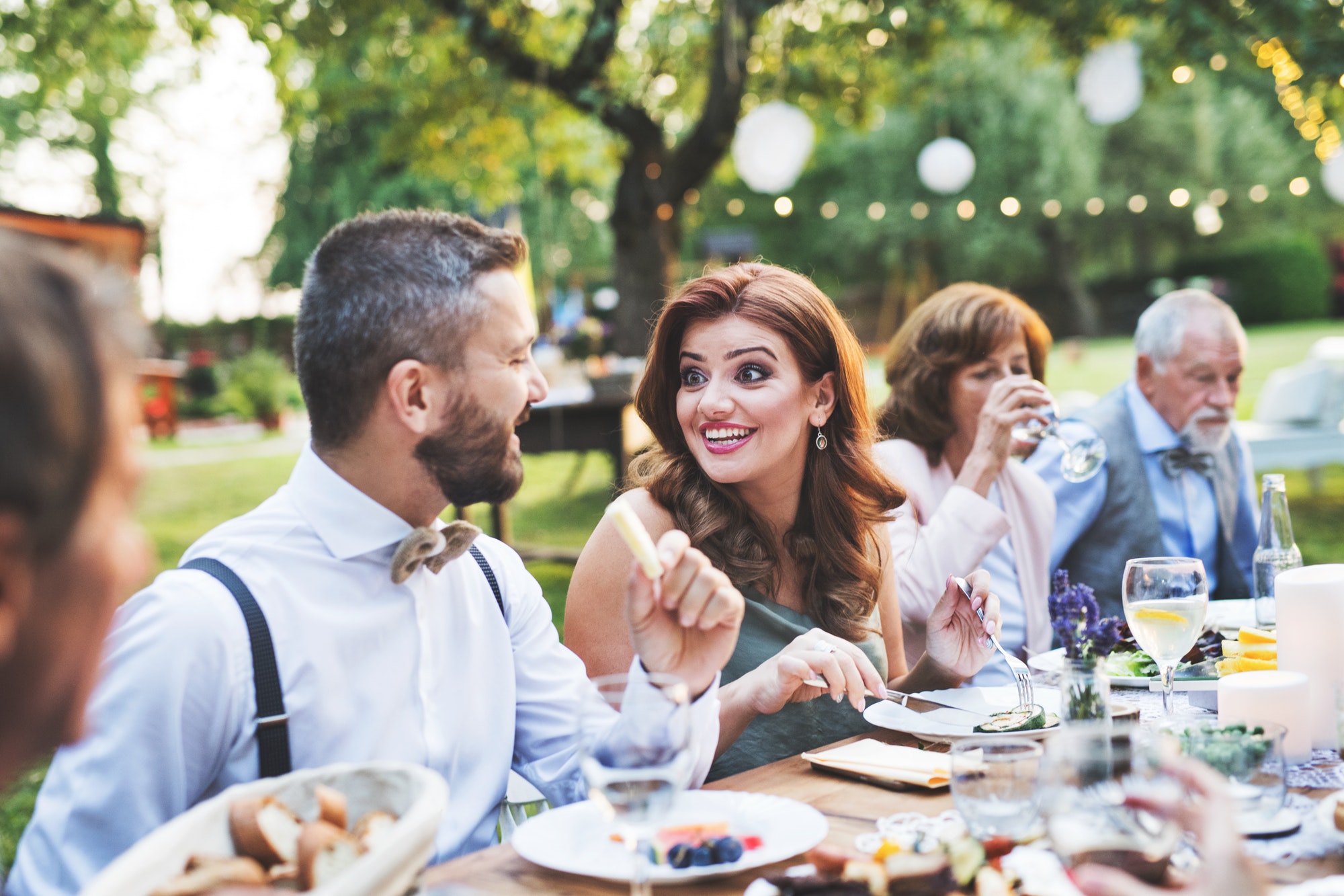 Guests eating at the wedding reception outside in the backyard.