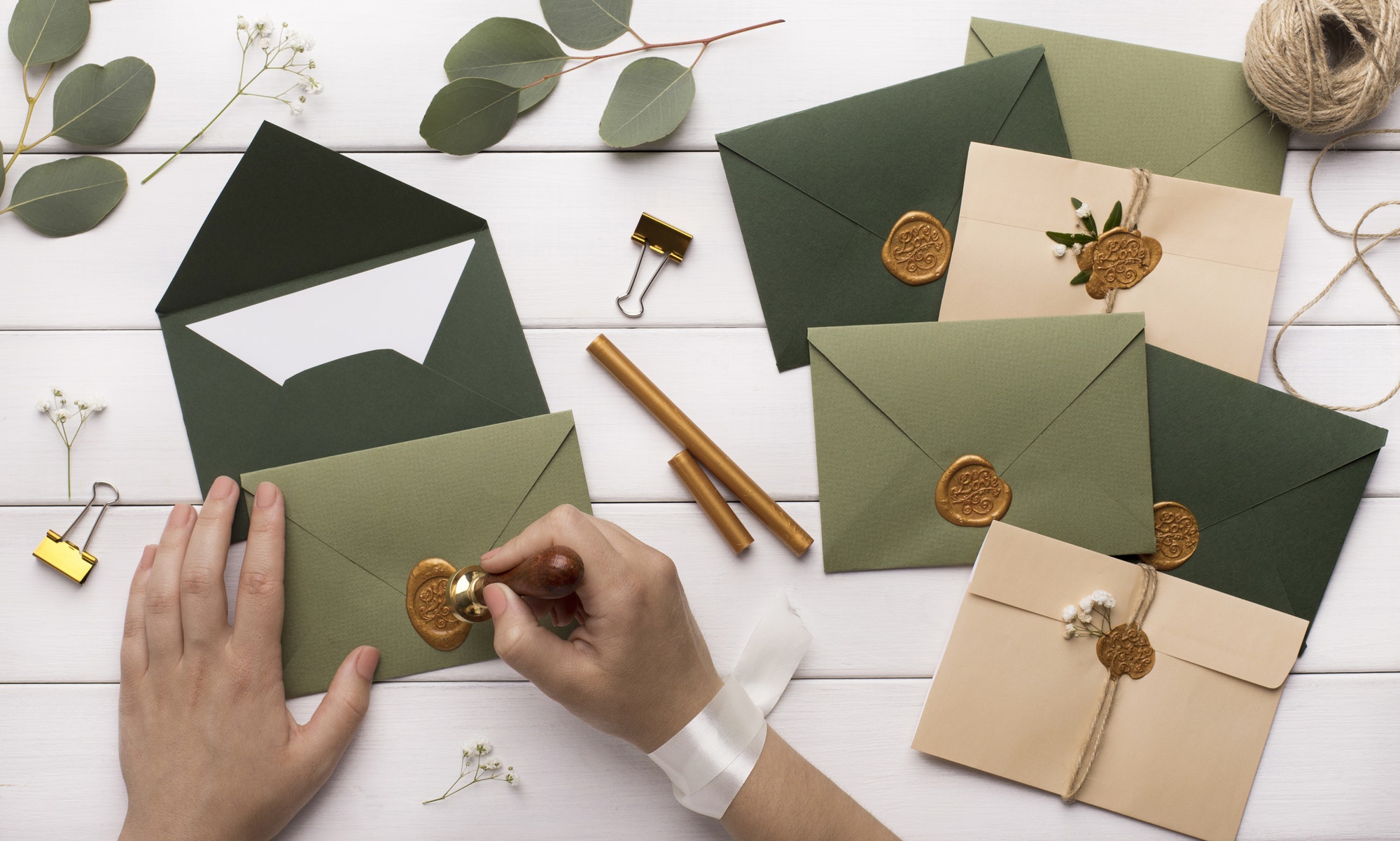 Woman preparing invitations for wedding on white wooden table