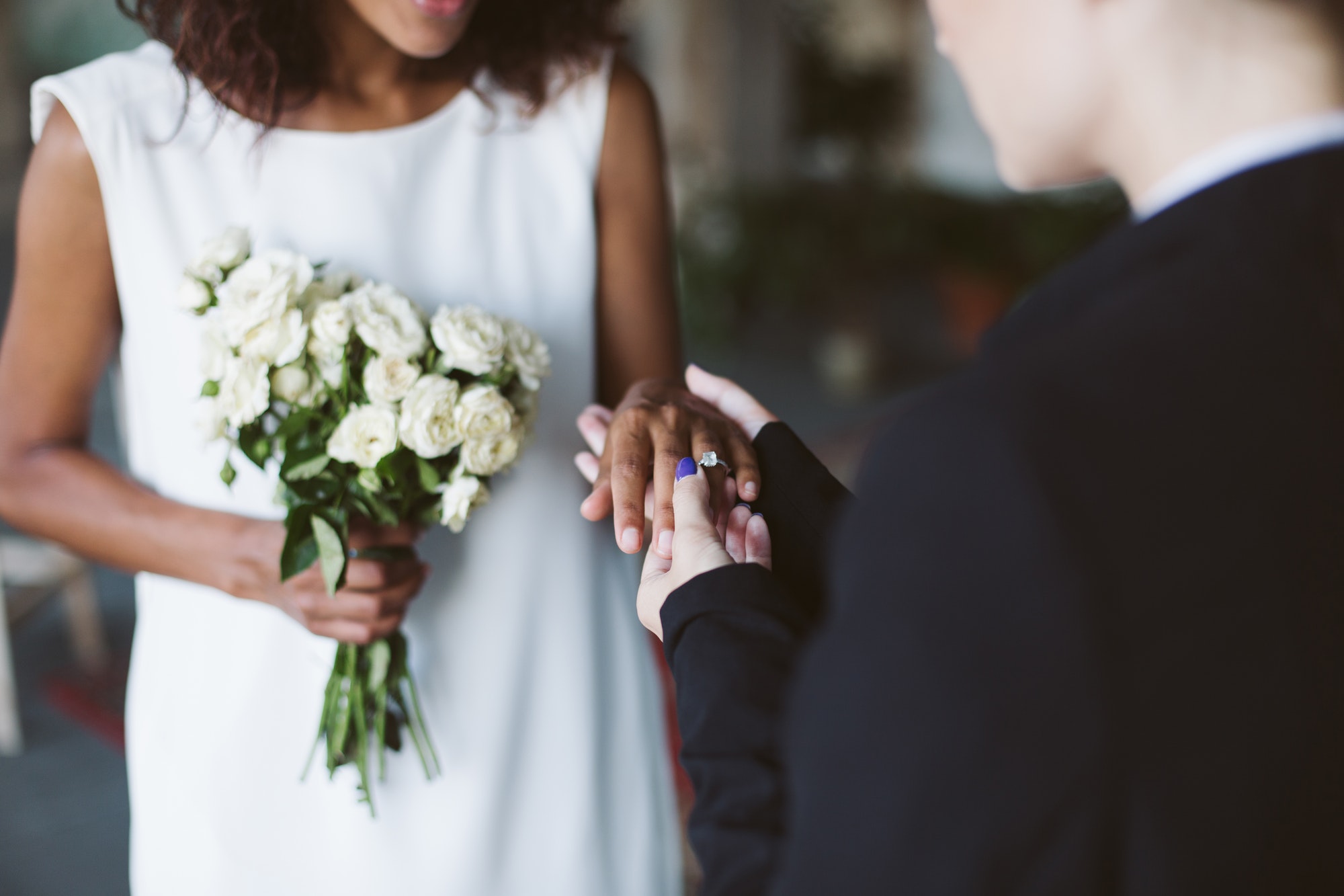 Close up woman in black suit putting a wedding ring on beautiful